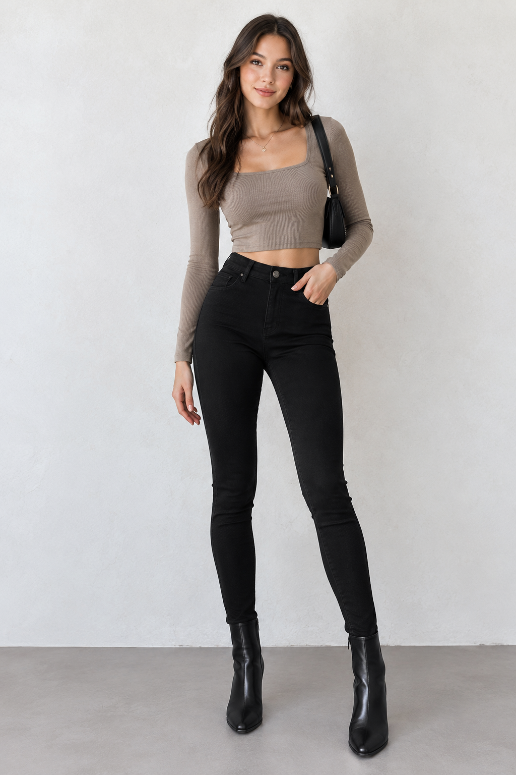 Model wearing black high-waisted skinny jeans with a taupe top and black ankle boots